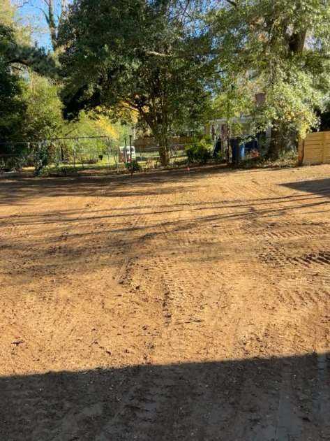 Bare compacted soil in a shaded Simpsonville SC backyard before sod installation